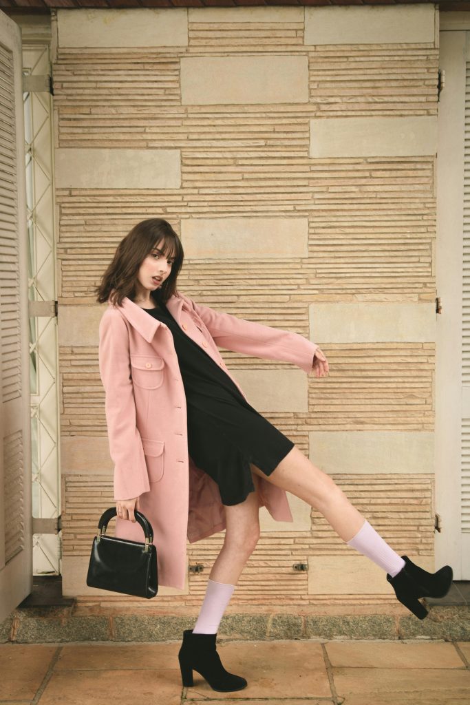 pexels-photo-2043590-2043590-2 Fashion model in pink coat and black dress striking a dynamic pose indoors with stylish black heels.